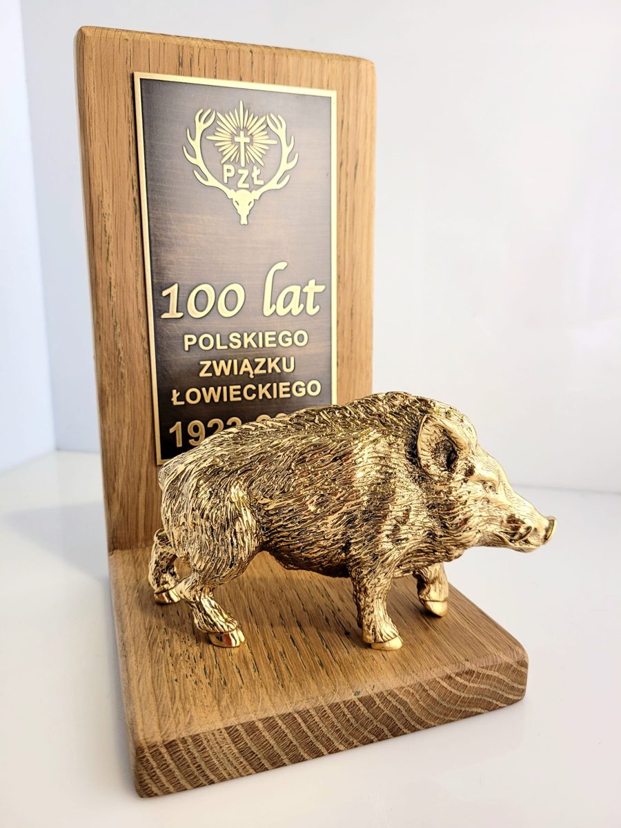 Złocona statuetka dzika na drewnianej podstawie z tabliczką 100 lat Polskiego Związku Łowieckiego